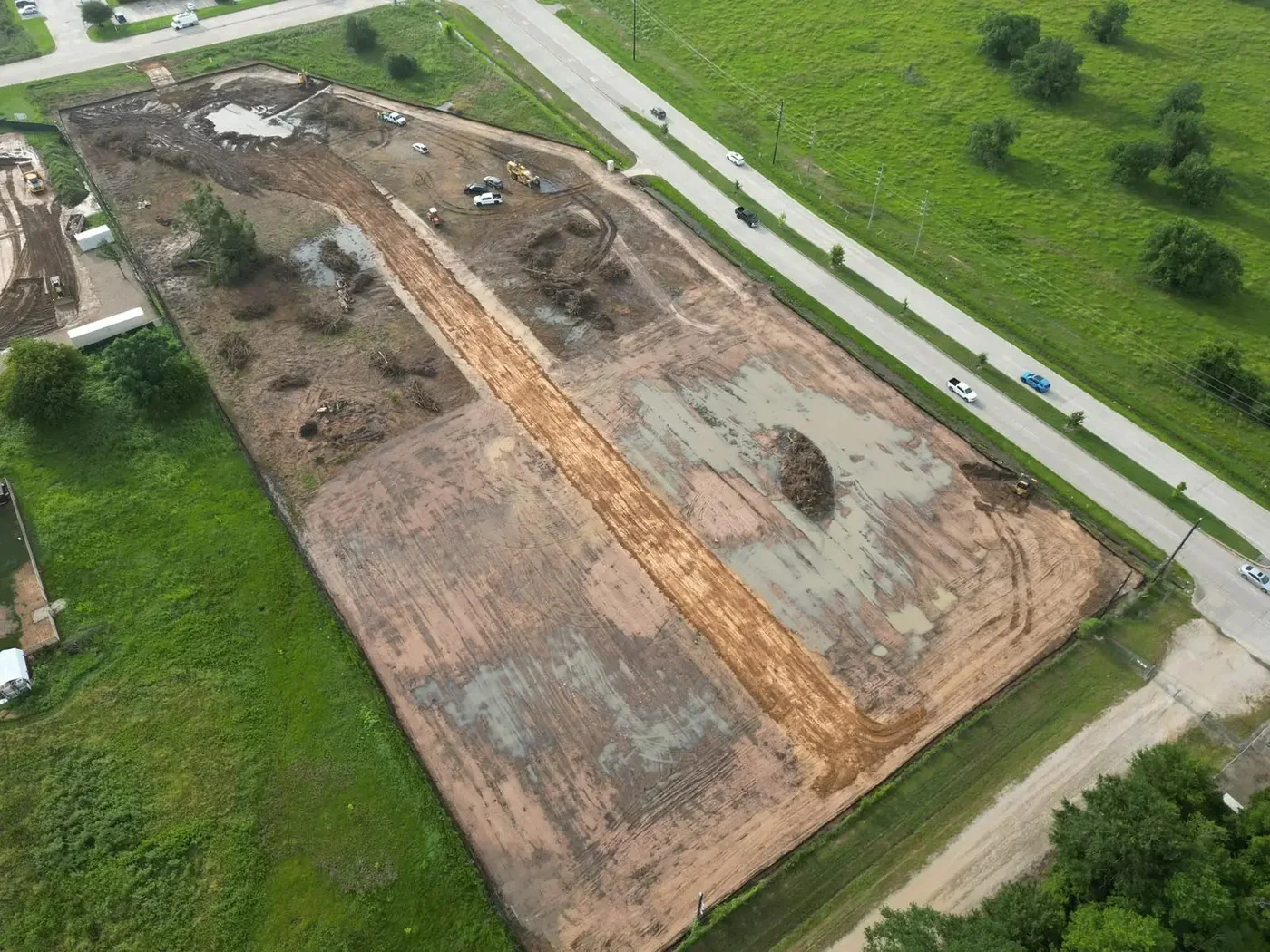 Aerial view of a large commercial site during clearing and topsoil stripping with stockpiles along the perimeter