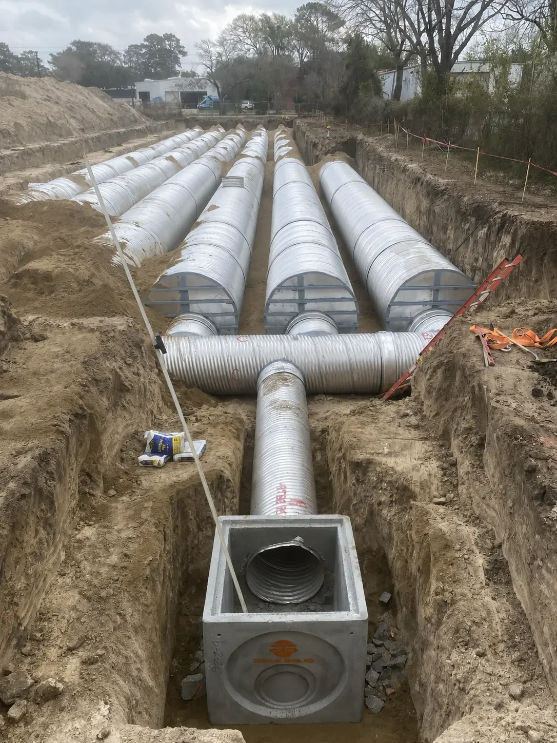 Commercial Site Development — Concrete junction box structure connected to a corrugated metal pipe manifold in an open dirt trench