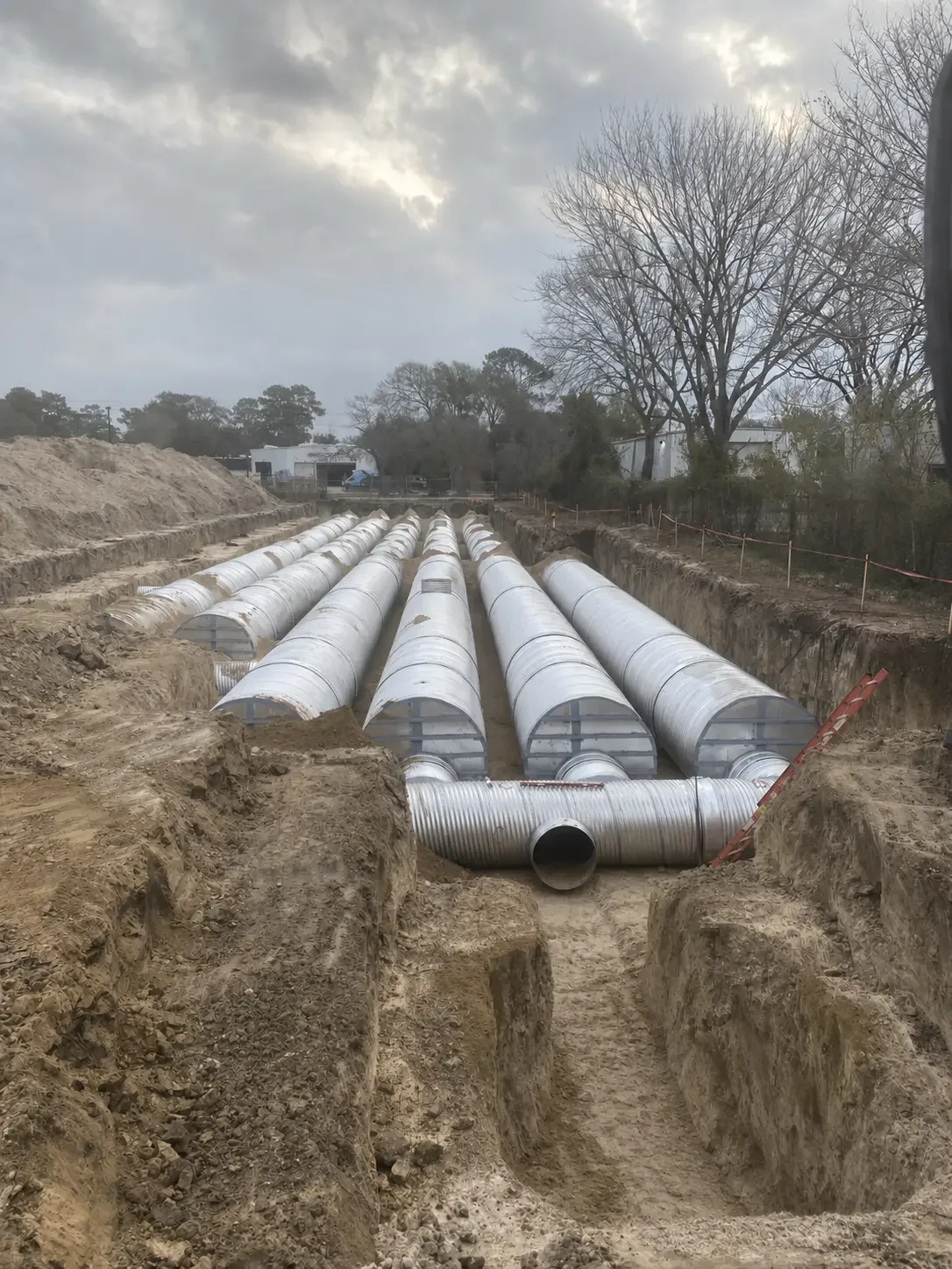 Wide view of an underground detention field with parallel rows of corrugated metal pipe connected to a header manifold