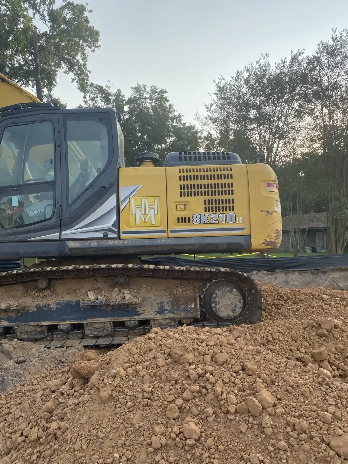 Tracked Kobelco excavator on an active earthwork site.