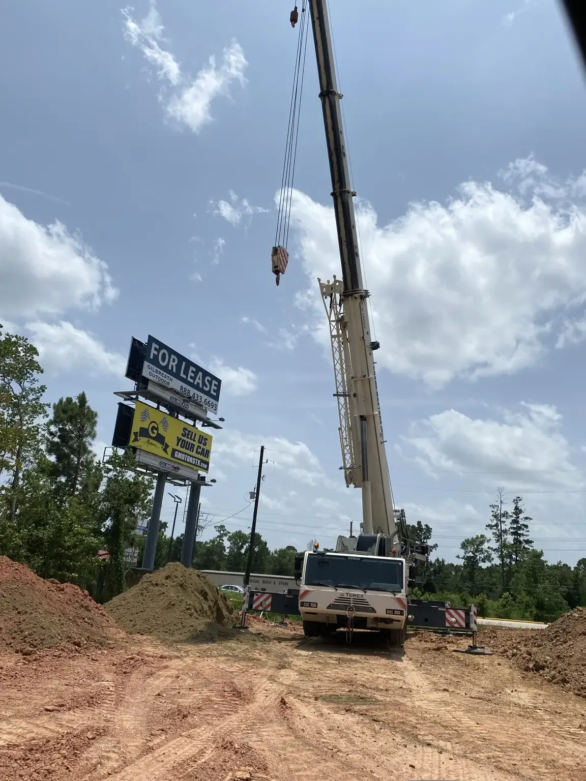 Mobile crane set up on a construction site under a bright sky.