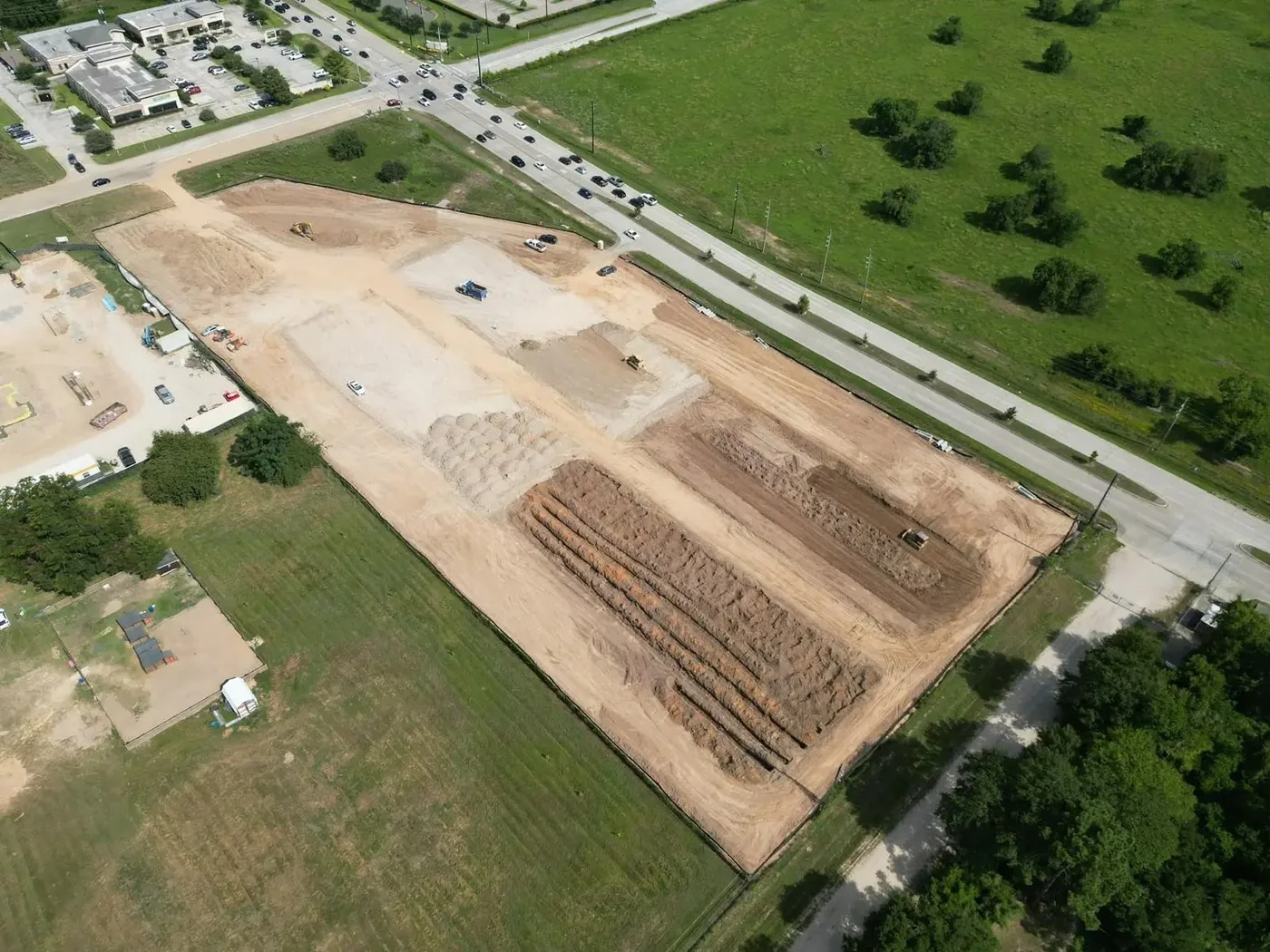 High angle aerial view of a construction site during mass grading with dirt stockpiles and heavy equipment working