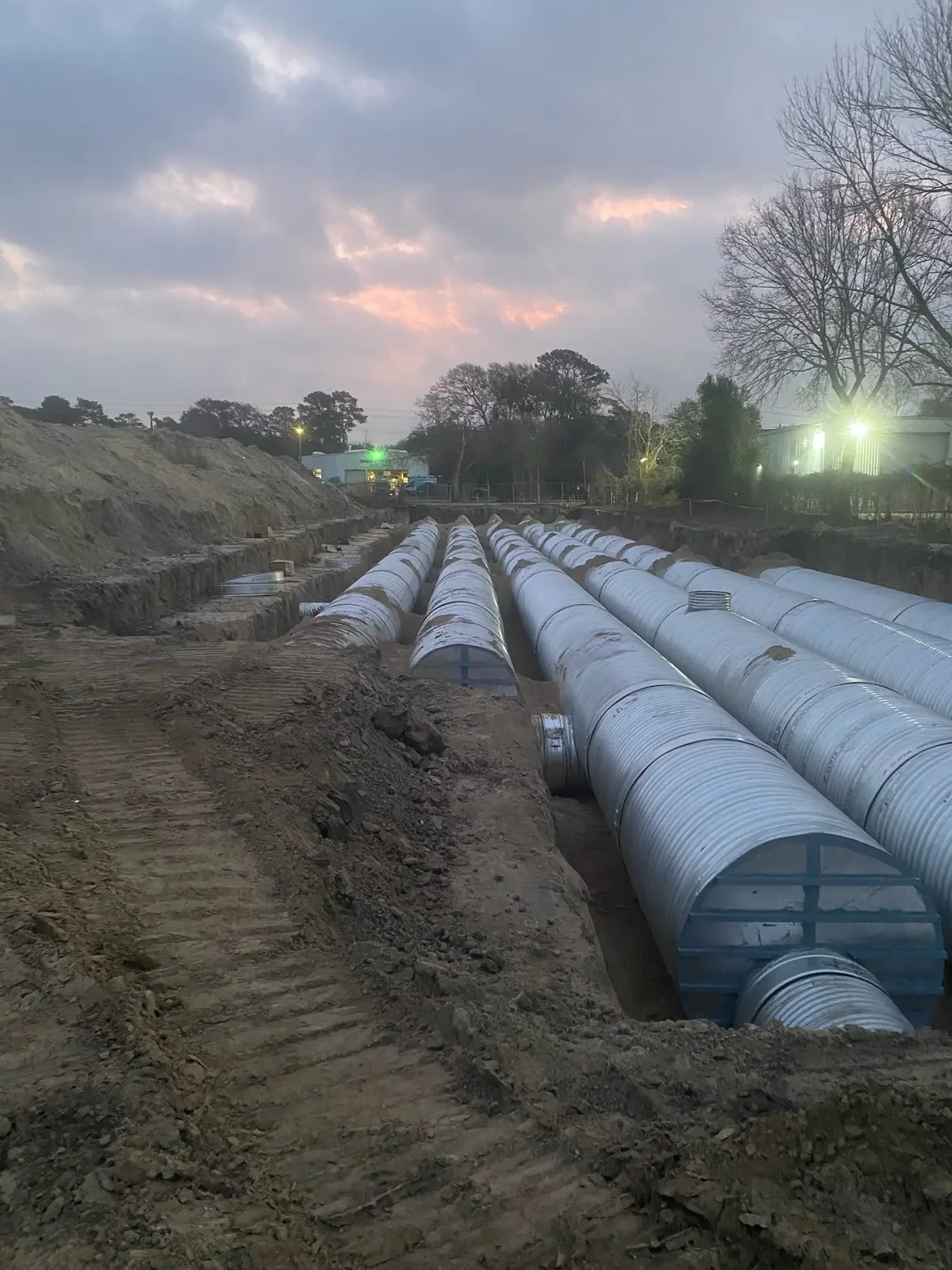 Commercial Site Development — Underground detention field of corrugated metal pipe photographed at dusk under a colored sky