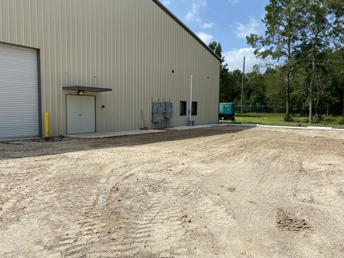 Fine graded subgrade prepared for paving next to a large metal commercial building